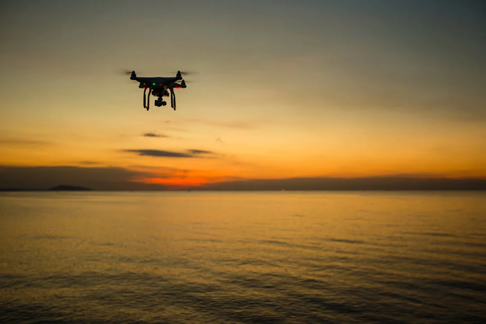 Drone capturing aerial footage over the ocean at sunset for cinematic video storytelling
