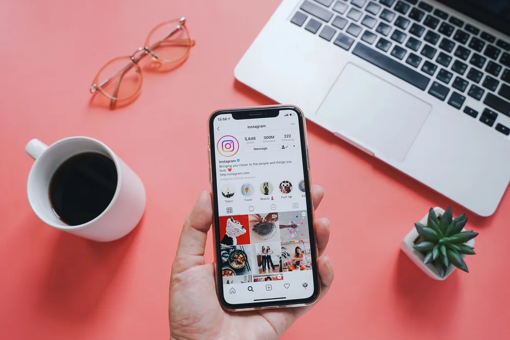 Open Instagram business account in palm of hand in front of a laptop