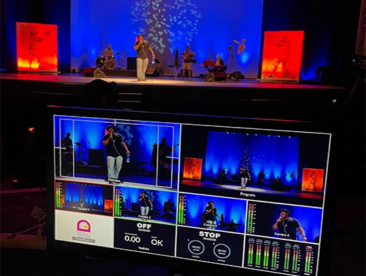 An example of a band playing on stage as a video producer live stream's the event online