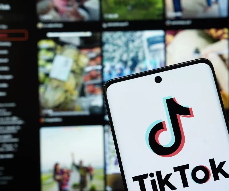 Tiktok app open on a phone in front of a computer screen